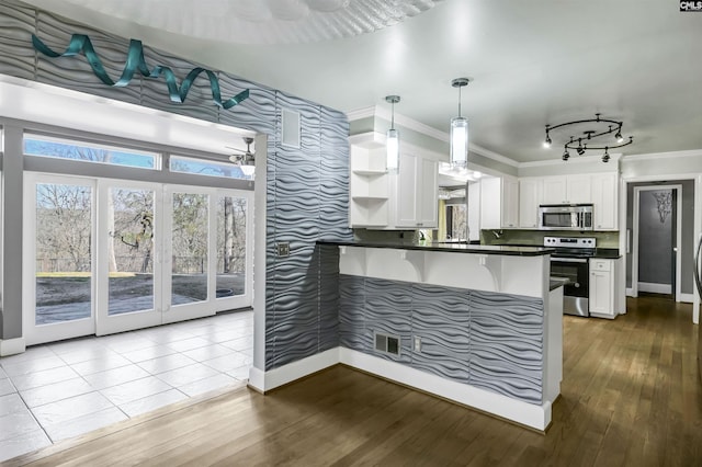 kitchen with pendant lighting, white cabinetry, stainless steel appliances, ornamental molding, and kitchen peninsula