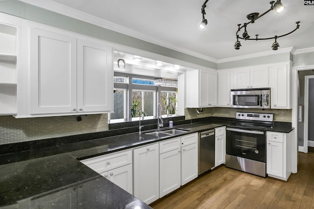 kitchen with appliances with stainless steel finishes, white cabinetry, sink, hardwood / wood-style flooring, and ornamental molding