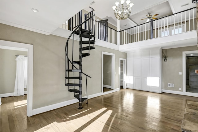 entryway with hardwood / wood-style flooring, ceiling fan, ornamental molding, and a high ceiling