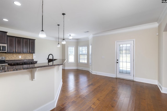 kitchen with dark wood-type flooring, dark brown cabinets, hanging light fixtures, a kitchen breakfast bar, and stainless steel appliances