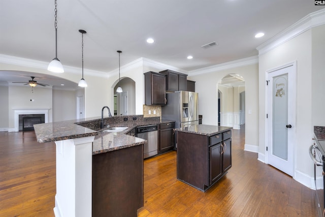 kitchen with dark stone countertops, appliances with stainless steel finishes, sink, and pendant lighting