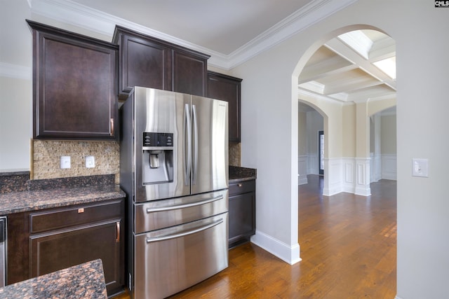 kitchen with dark wood-type flooring, dark stone countertops, stainless steel appliances, tasteful backsplash, and ornamental molding