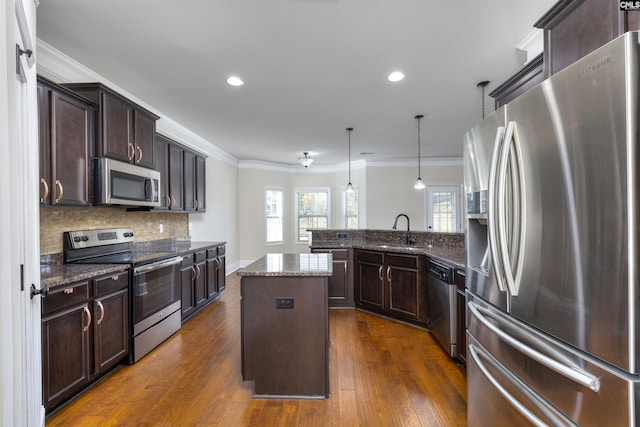 kitchen featuring sink, a center island, hanging light fixtures, appliances with stainless steel finishes, and kitchen peninsula