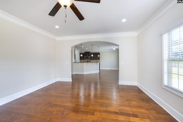 unfurnished living room with crown molding, plenty of natural light, ceiling fan, and dark hardwood / wood-style flooring