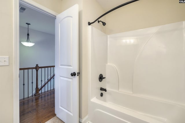 bathroom featuring hardwood / wood-style flooring and washtub / shower combination