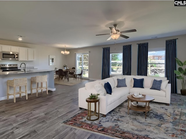 living room with sink, ceiling fan with notable chandelier, light hardwood / wood-style flooring, and plenty of natural light