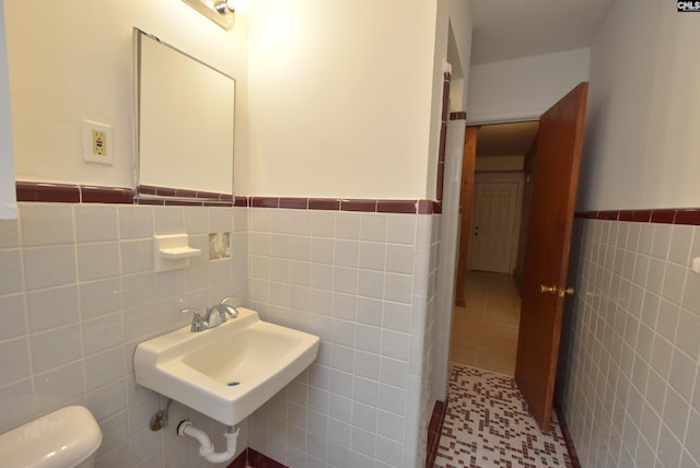 bathroom featuring tile patterned flooring, sink, tile walls, and toilet