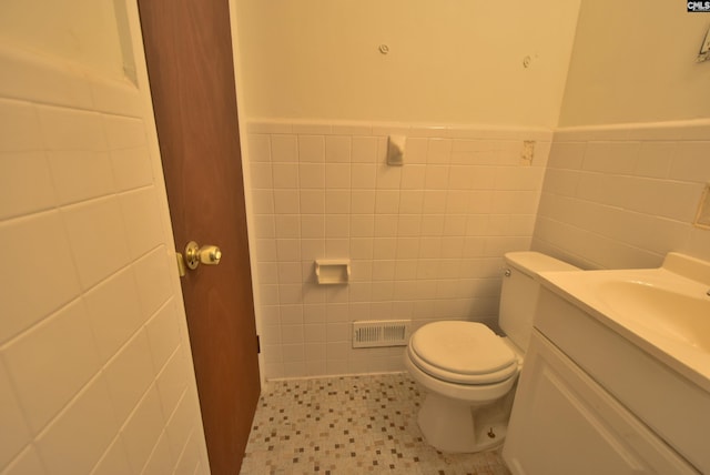 bathroom with tile walls, vanity, and toilet