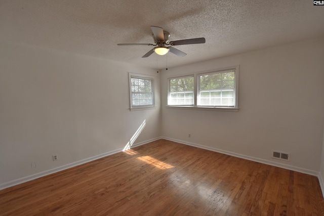 empty room featuring ceiling fan, hardwood / wood-style flooring, plenty of natural light, and a textured ceiling