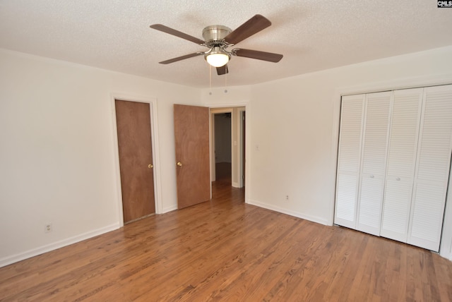 unfurnished bedroom featuring ceiling fan, wood-type flooring, a closet, and a textured ceiling