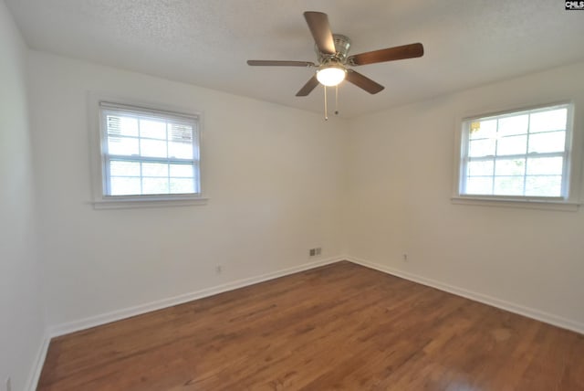 unfurnished room featuring ceiling fan, plenty of natural light, dark hardwood / wood-style floors, and a textured ceiling