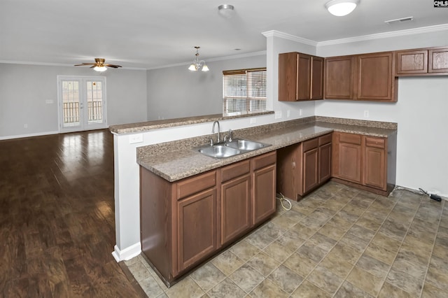 kitchen featuring sink, hardwood / wood-style flooring, hanging light fixtures, ornamental molding, and kitchen peninsula