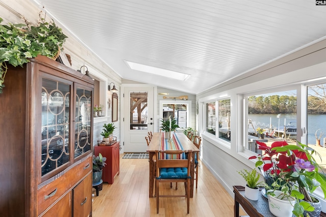 sunroom featuring lofted ceiling with skylight and a water view