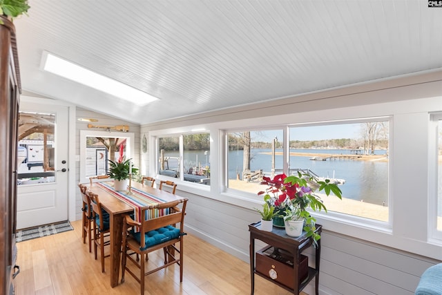 sunroom with a water view, plenty of natural light, and vaulted ceiling