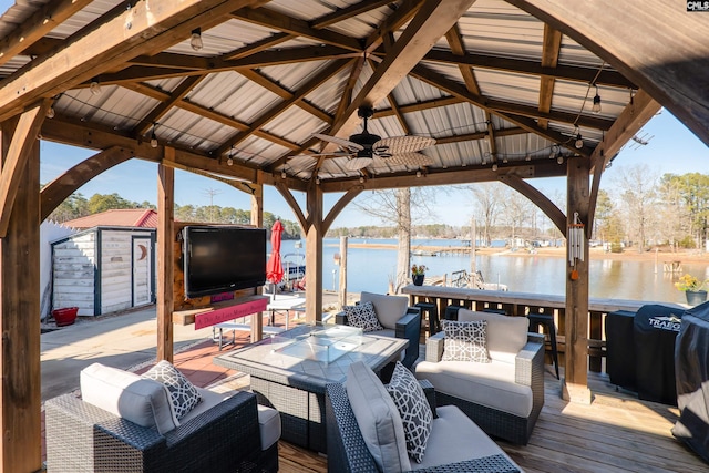 wooden deck featuring a storage shed, a gazebo, grilling area, outdoor lounge area, and ceiling fan