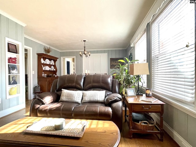 living room with an inviting chandelier, light hardwood / wood-style flooring, and ornamental molding