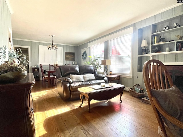 living room featuring ornamental molding, wood-type flooring, and a notable chandelier