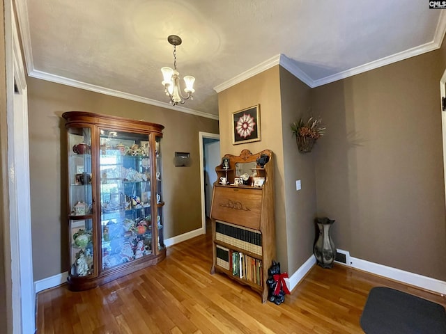 interior space with an inviting chandelier, hardwood / wood-style flooring, and crown molding