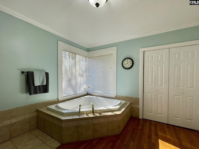 bathroom featuring a relaxing tiled tub, crown molding, and hardwood / wood-style floors