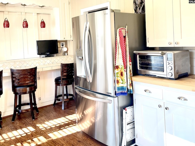 kitchen with stainless steel fridge with ice dispenser, decorative backsplash, dark hardwood / wood-style floors, and white cabinets