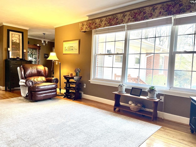 sitting room with hardwood / wood-style flooring, ornamental molding, and a chandelier