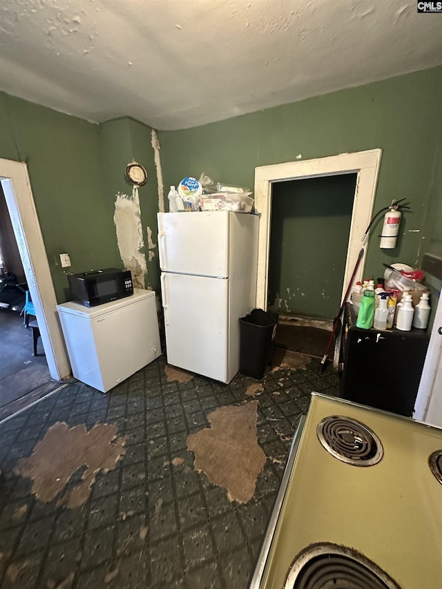 kitchen with black microwave, range, and freestanding refrigerator