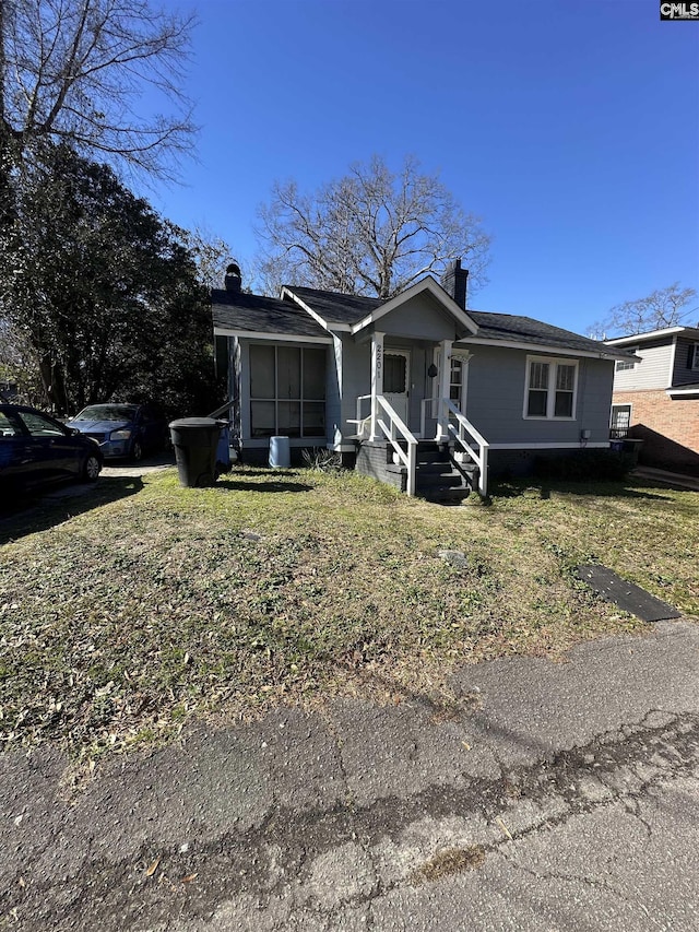 view of front of home with a chimney and a front lawn