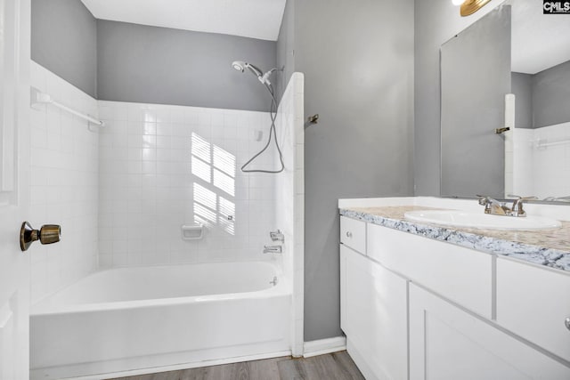 bathroom with hardwood / wood-style flooring, vanity, and tiled shower / bath combo