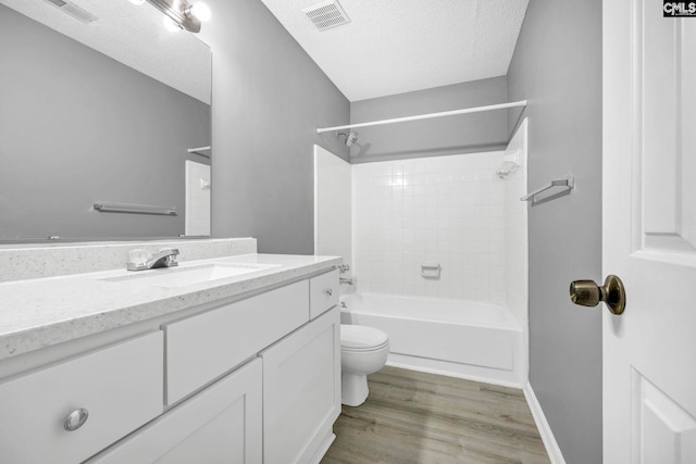 full bathroom featuring toilet, tiled shower / bath, a textured ceiling, vanity, and hardwood / wood-style flooring