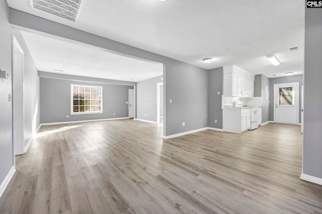 unfurnished living room with light hardwood / wood-style floors and a textured ceiling