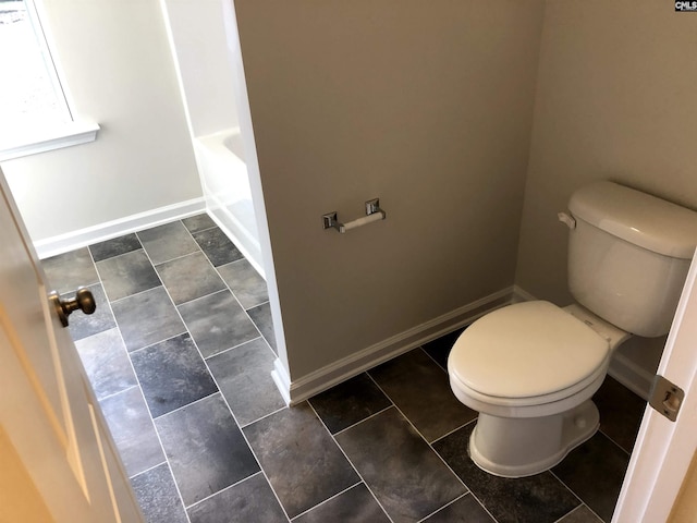 bathroom featuring tile patterned floors, a tub, and toilet