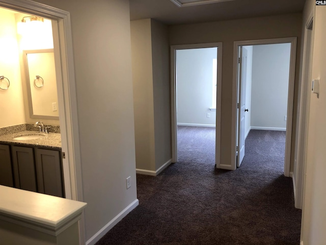 hallway featuring sink and dark colored carpet