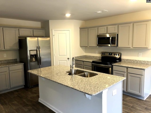 kitchen with light stone countertops, an island with sink, appliances with stainless steel finishes, and sink