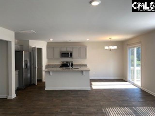 kitchen featuring gray cabinets, appliances with stainless steel finishes, a breakfast bar area, hanging light fixtures, and dark wood-type flooring