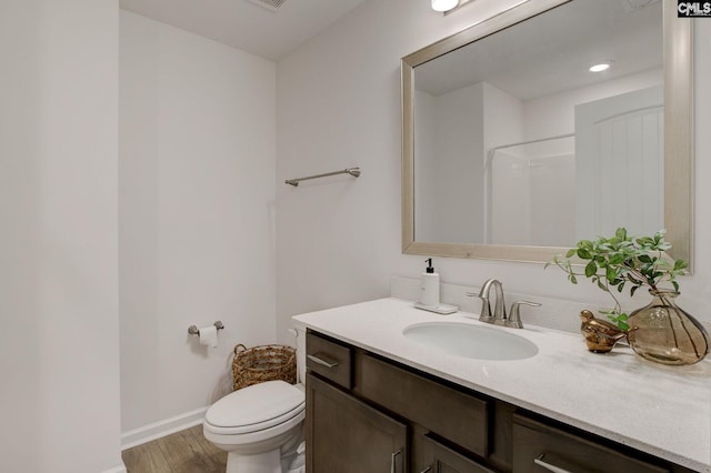 bathroom featuring hardwood / wood-style flooring, vanity, toilet, and walk in shower