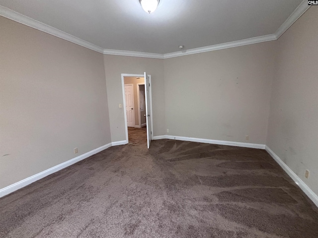 spare room featuring ornamental molding, dark colored carpet, and baseboards