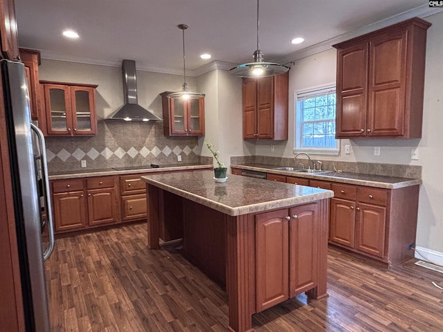 kitchen with glass insert cabinets, wall chimney range hood, freestanding refrigerator, a center island, and decorative light fixtures