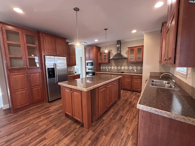 kitchen with glass insert cabinets, a center island, hanging light fixtures, stainless steel appliances, and wall chimney range hood