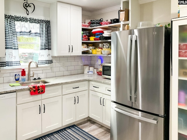 kitchen with sink, white cabinets, ornamental molding, stainless steel appliances, and light stone countertops