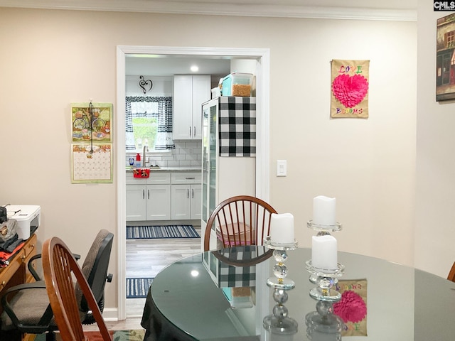 dining room featuring sink, crown molding, and light hardwood / wood-style flooring