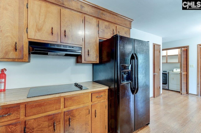 kitchen featuring light wood-type flooring, washer and dryer, and black appliances