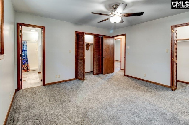 unfurnished bedroom featuring ensuite bathroom, a walk in closet, light carpet, a closet, and ceiling fan