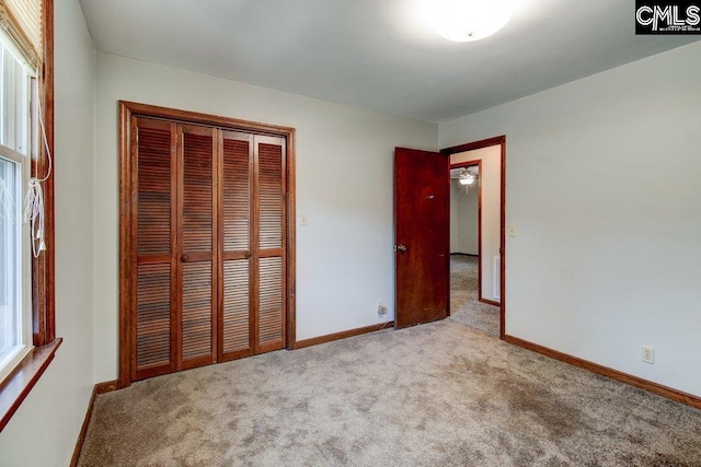 unfurnished bedroom with light colored carpet and a closet