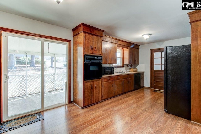 kitchen with light hardwood / wood-style floors and black appliances