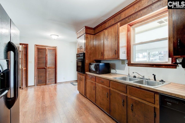 kitchen featuring light wood-type flooring, sink, and black appliances