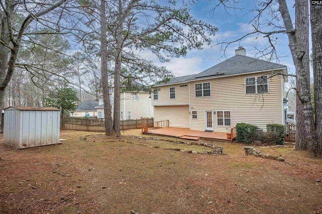 back of property featuring a yard, a deck, and a storage unit