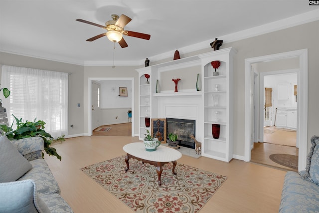 living room featuring ceiling fan, ornamental molding, and light wood-type flooring