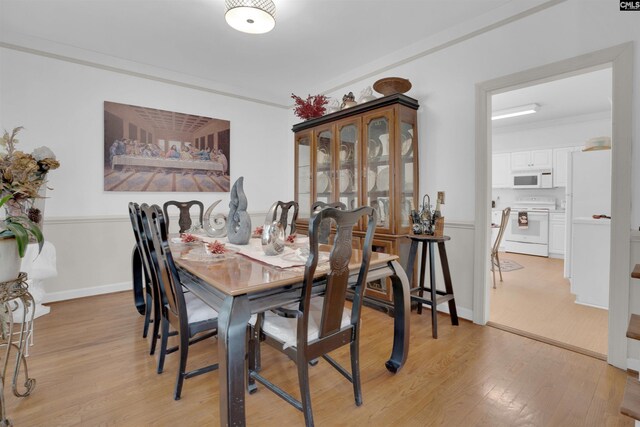 dining space featuring crown molding and light wood-type flooring