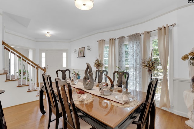 dining space with ornamental molding and light hardwood / wood-style flooring