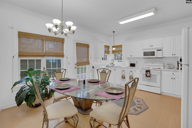dining area with ornamental molding, a chandelier, sink, and light hardwood / wood-style flooring